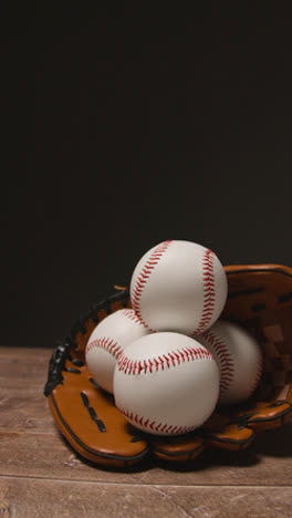 Vídeo-Vertical-De-Cerca-Estudio-De-Béisbol-Bodegón-Con-Pelotas-Y-Guantes-De-Receptor-En-El-Suelo-De-Madera